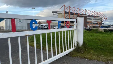Vue générale du stade d'Inverness Caledonian Thistle, avec une clôture portant les lettres I C T F C.