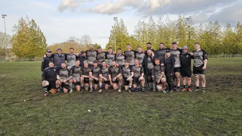 Équipe de rugby Cross Keys RFC couverte de boue sur un terrain détrempé