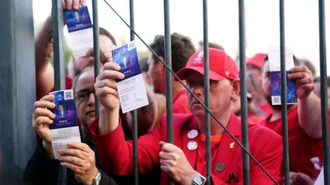 Supporters de Liverpool montrant leurs billets devant une grille