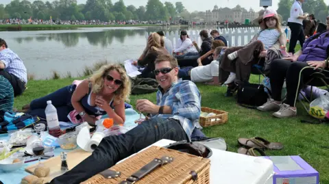 Jeune couple pique-niquant avec leurs enfants près d’un obstacle d’eau