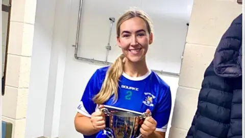 Aislín Ní Choinn, joueuse de camogie, posant avec un trophée