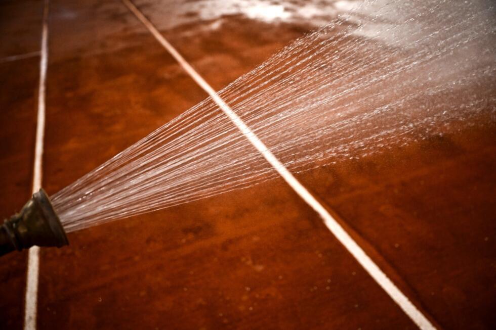 Un membre du personnel arrose le court Philippe-Chatrier, avant Roland-Garros, à Paris le 21 mai 2025.