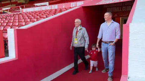 Alan Moore, son fils Matt et son petit-fils sortant du tunnel vers la pelouse