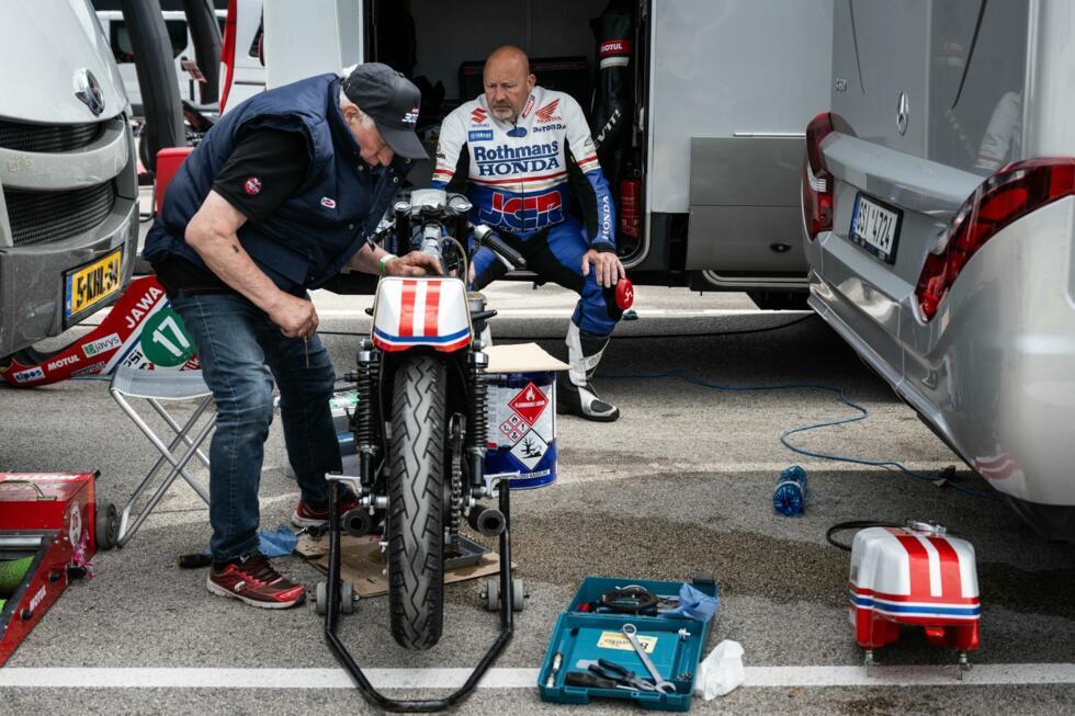 Un motard inspecte sa moto vintage avant de participer à la course Moto Légende sur le circuit de Dijon-Prenois, le 25 mai 2025 à Prenois, en Côte-d'Or