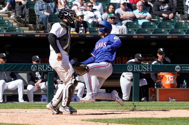 Kyle Higashioka du Texas Rangers marque alors que le receveur des White Sox, Edgar Quero, observe lors du neuvième inning du dimanche à Chicago. (AP Photo/David Banks)