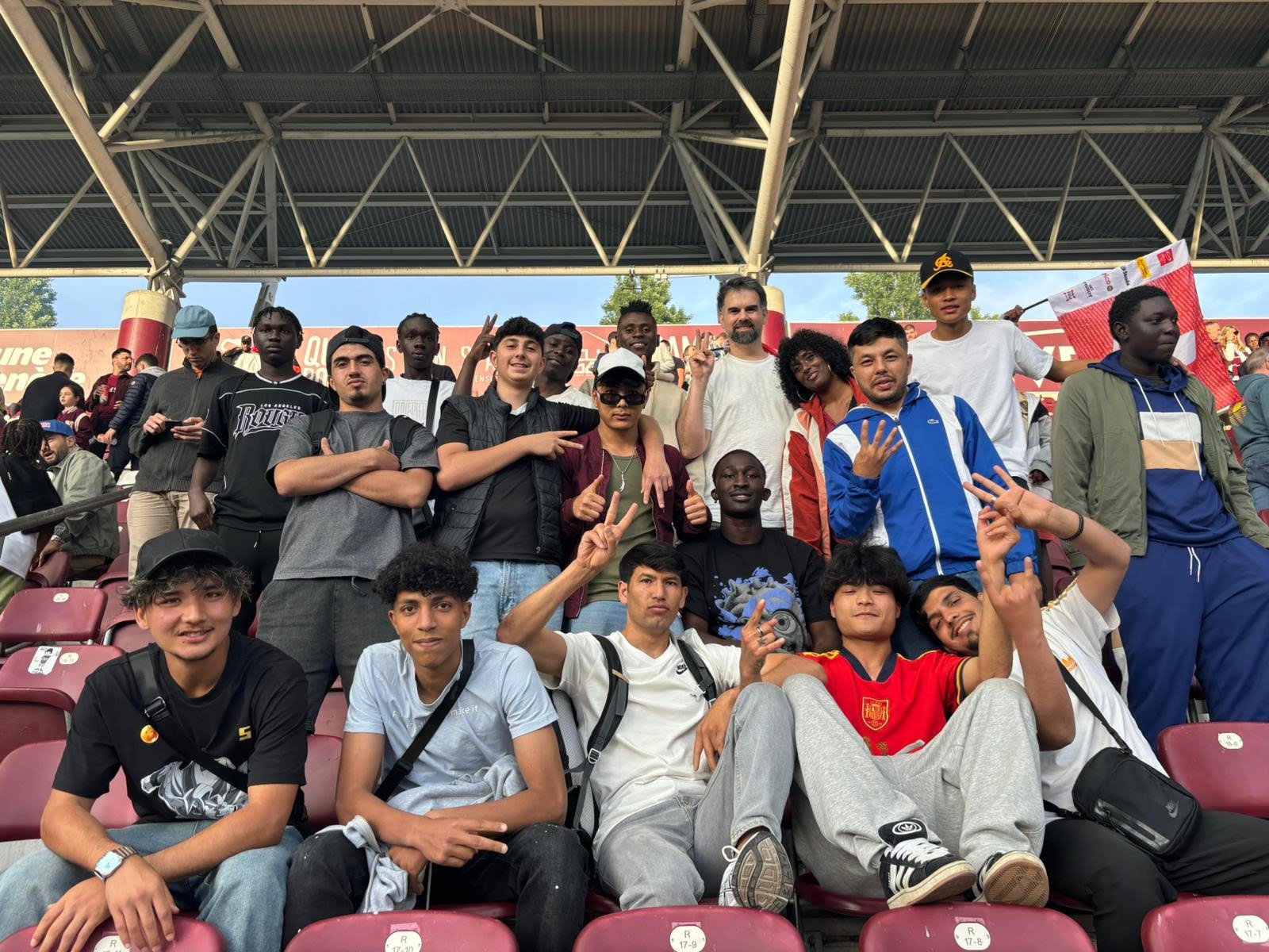 Des jeunes jouent au football dans un petit terrain, entouré de graffitis, avec des immeubles résidentiels en arrière-plan.